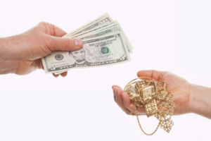 Hands exchanging jewelry for cash. Pawn loan available in KL Selangor.